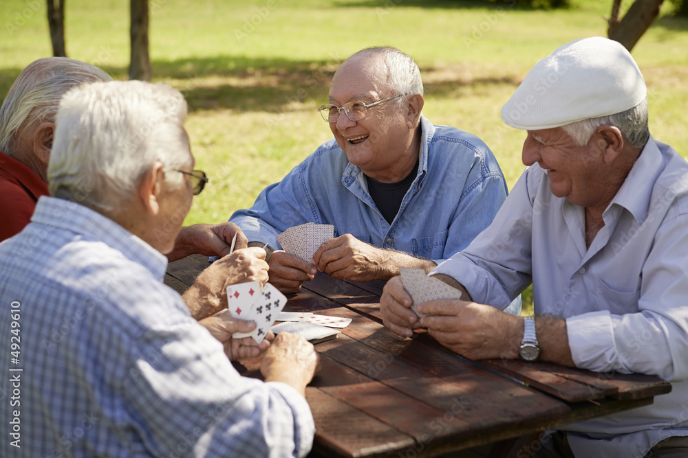 Active seniors, group of old friends playing cards at park