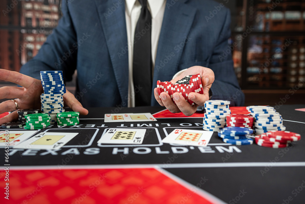 Gambler man hands pushing chips and going all-in in poker game at casino